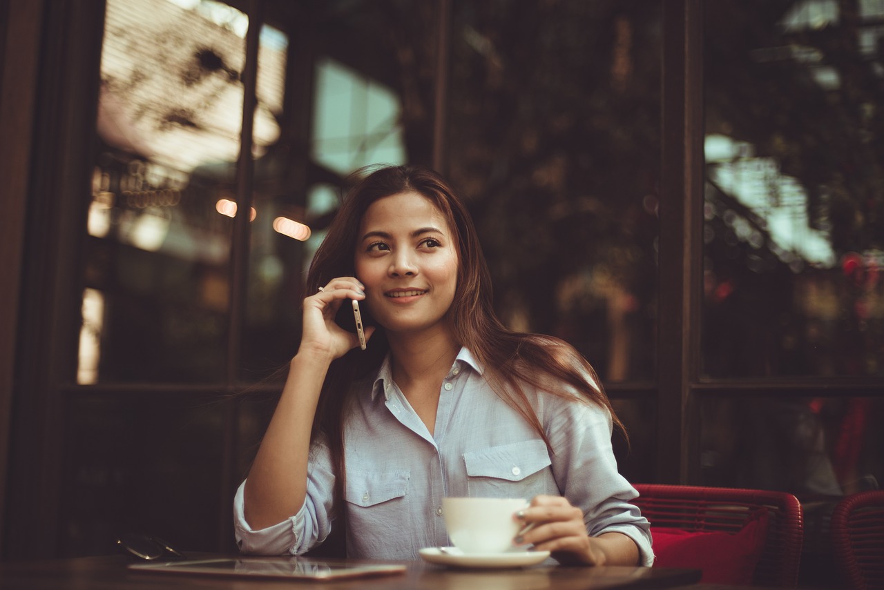 Business lady talking on the phone while sitting in a café, balancing work and a relaxed environment.